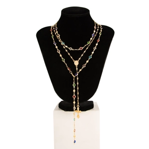 Dettaglio della collana multistrato dorata con pietre colorate, medaglione e croce pendente