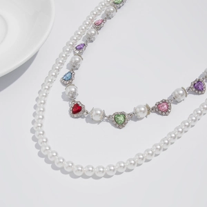 Close-up of double-layer necklace with white faux pearls and colorful heart gemstones