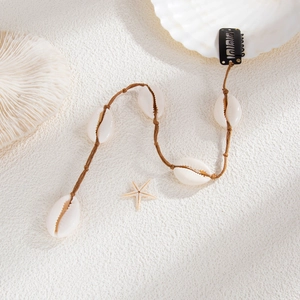 Détail de pinces à cheveux bohème coquillage sur fond texturé à thème plage d'été