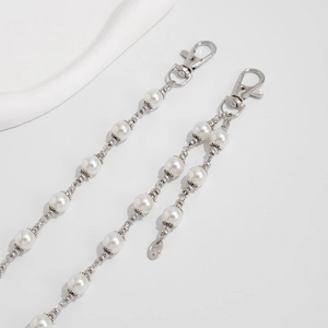 Close-up of silver punk chain belt with white pearls and smiling moon pendant charm