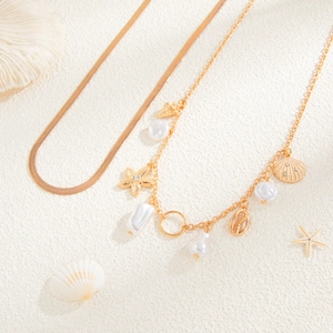 Detail of gold snake chain with shell, starfish pendants and pearls for beach vacation