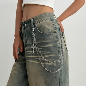 Detail view of multi-layer silver pants chain with cross pendant on denim jeans