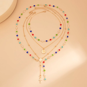 Dettaglio collana a strati dorata con pietre preziose colorate e ciondoli a croce