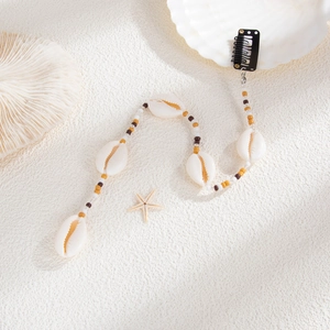 Détail de pince à cheveux de plage avec cauris naturels et perles bohèmes sur fond blanc