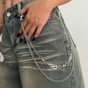 Détail de la chaîne de taille punk argentée avec breloques flamme et épines sur jean