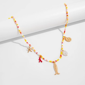 Detail of beaded waist chain with gold starfish, coral, and shells on white background
