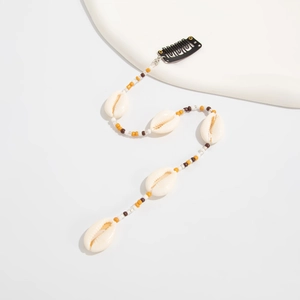 Détail d'une pince à cheveux bohème avec perles colorées et pendentifs coquillages