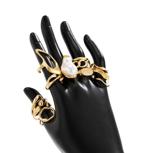 Detailed view of layered golden rings with baroque pearl and organic fluid metal shapes