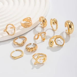 Close-up of 11-piece gold ring set featuring faux pearls on white podiums
