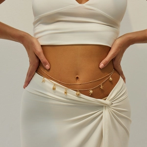 Detail of gold layered belly chain with starfish, shell, and palm tree charms on model