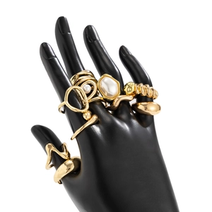 Macro view of gold droplet rings and Baroque pearls on a black display stand
