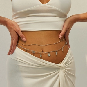 Close-up of silver waist chain with starfish, shell, and palm tree charms on a model