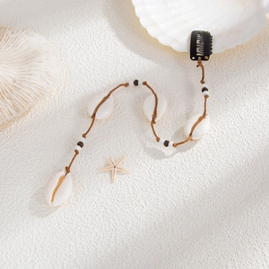 Détail de pince à cheveux de plage avec coquillages cauris et perles