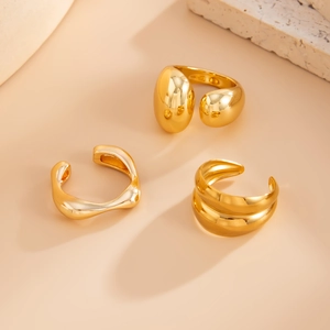 Détail de trois bagues dorées aux formes organiques avec finition miroir minimaliste