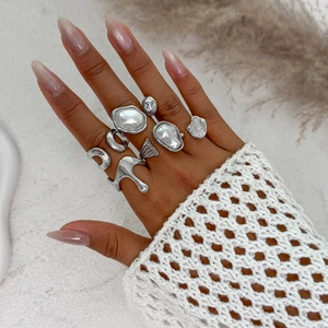 Detailed view of silver irregular metal rings with imitation pearl inlay on model hand