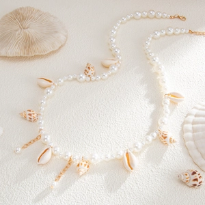 Seashell and pearl body chain with starfish pendant on a sandy beach background