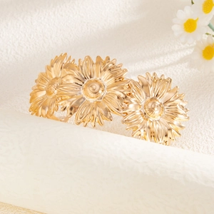Detailweergave van de gouden madeliefjes servetring met drie bloemen en gepolijst metaal