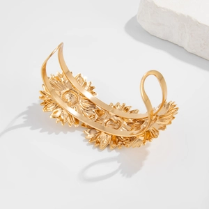 Detail van een gouden zonnebloem armband met vintage reliëf en metalen texturen