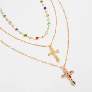 Dettaglio della collana a tre strati dorata con gemme colorate e ciondoli a croce