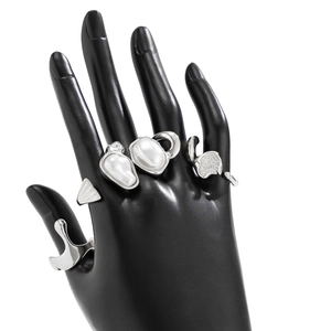 Detail of silver water drop rings set with baroque pearls on a black hand model