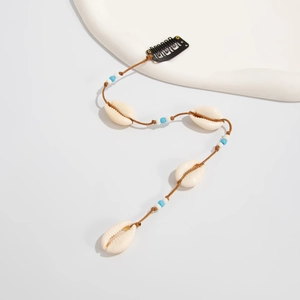 Détail d'une pince à cheveux bohème avec coquillages naturels et perles bleues