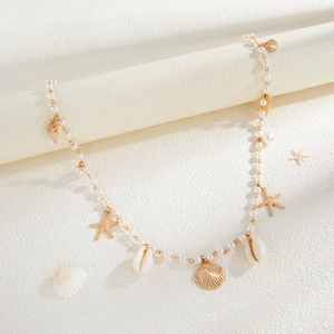 Detailed view of starfish shell charms and white pearls on a gold-plated body chain