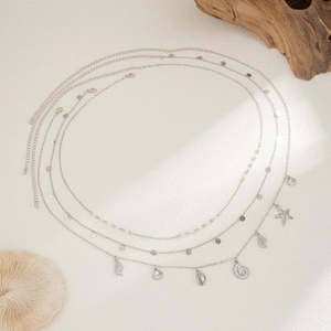 Close-up of a silver multi-layer waist chain with starfish, shell pendants and pearls