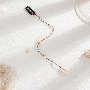 Détail de pince à cheveux bohème avec étoile de mer, coquillage et cordon tressé perlé