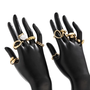 Detailed view of stacked gold-finish irregular metal rings with white embossed floral accents