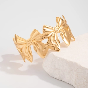 Detailopname van gouden armband met strikjes op een witte gestructureerde stenen basis