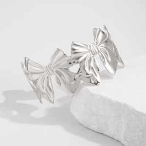 Detailopname van zilveren metalen armband met strikjes op witte getextureerde steen