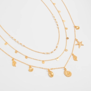 Close-up of gold-tone layered chain with starfish and seashell charms for summer resort style