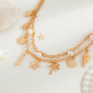 Macro view of gold-layered chain with starfish shells and pearl charms on sand