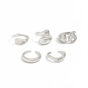 Détail du lot de cinq bagues et bijoux d'oreille argentés aux formes organiques fluides