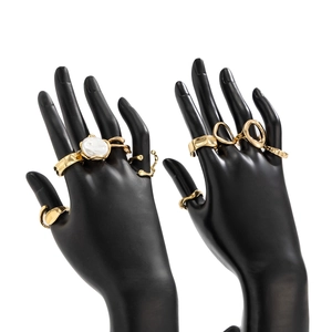 Detail of gold-tone irregular metal ring set featuring a baroque pearl on a black hand model