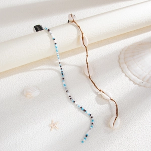 Détails d'accessoires de cheveux bohèmes avec coquillages et perles sur sable blanc