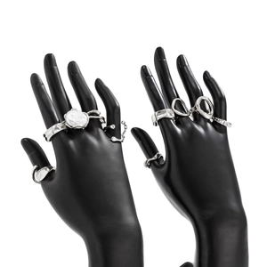 Detailed view of silver irregular metal rings with white pearls on a black hand model