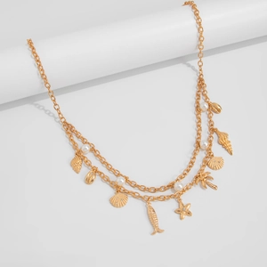 Detail view of a double-layer gold chain with starfish, shells, and pearls on a white stand