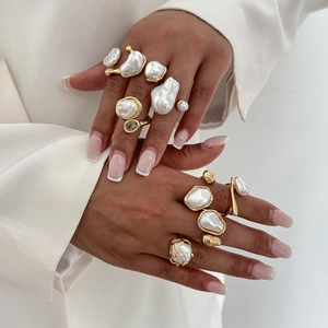 Close-up of irregular baroque pearl rings in gold metal finish worn on hand