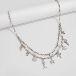 Close-up of layered silver body chain with starfish, seashell, and pearl charms