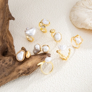 Detail view of baroque pearl rings with molten gold metal texture on natural sand