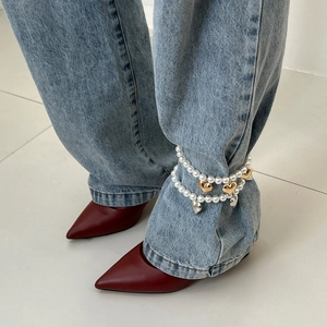 Faux pearl anklet chain with heart pendants worn with blue jeans and pointed shoes