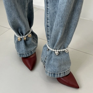 Bracelet de cheville en perles avec pendentif cœur porté avec un jean et talons