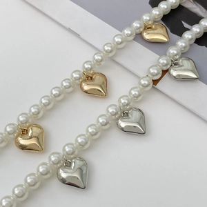 Detailed macro view showing gold and silver heart charms on white pearl necklaces