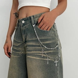 Detail of punk silver thorns chain with cross pendants on denim jeans for street style