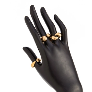 Détail de trois bagues dorées en métal liquide avec finition polie sur un mannequin de main