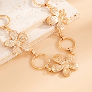 Detail of golden flower waist chain with textured petals and polished metallic finish