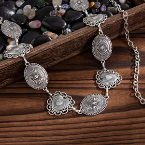 Close-up of bohemian silver waist chain with heart and sun embossed metal medallions
