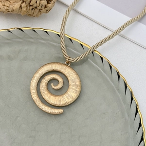 Goldene spiralförmige Muschel-Halskette mit geflochtener Kordel auf einem Dekotablett
