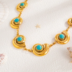 Macro shot of gold beach body chain with seashell charms and turquoise stone inlays